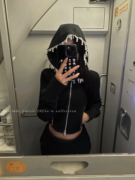 Black hooded zip-up top with pearl fringe detail worn by a model in a mirror selfie