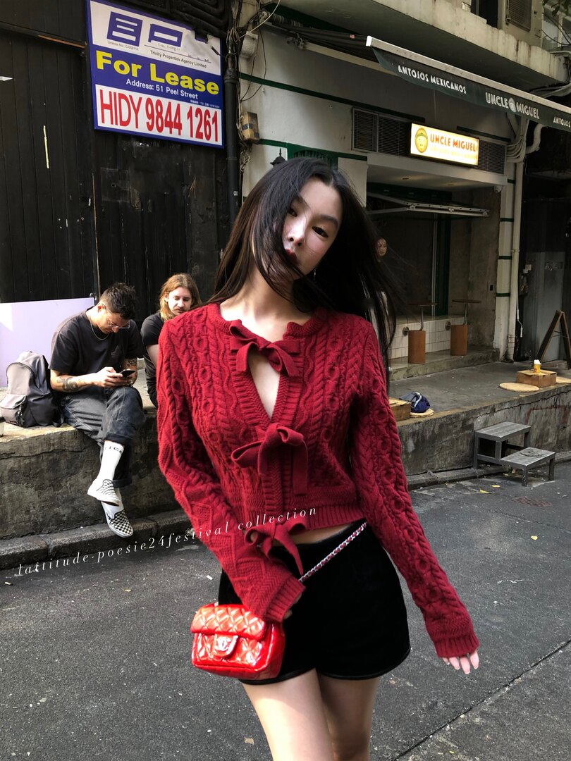 Woman wearing a red cable-knit bow sweater with black shorts and a red mini bag