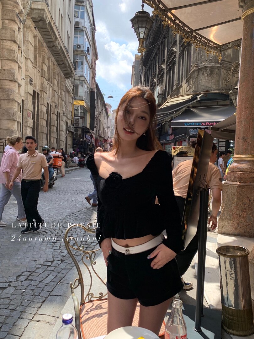 Woman wearing a black long-sleeve crop top and shorts outfit on a city street