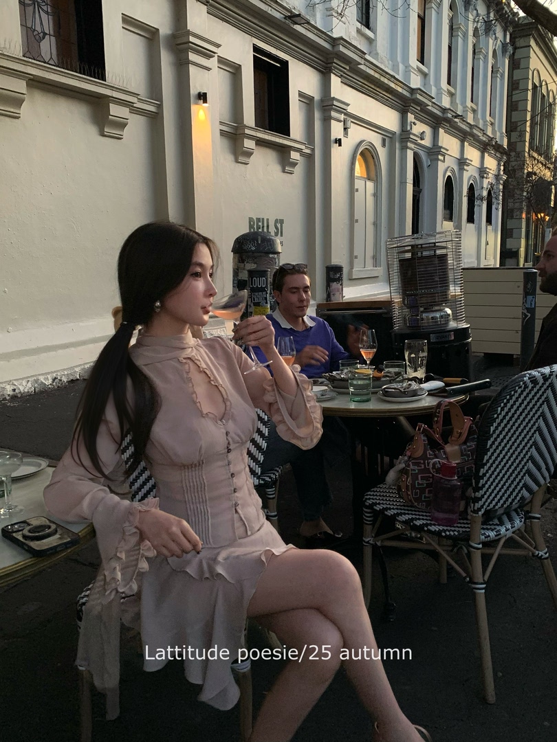 Model wearing a soft pink long-sleeve dress at an outdoor restaurant