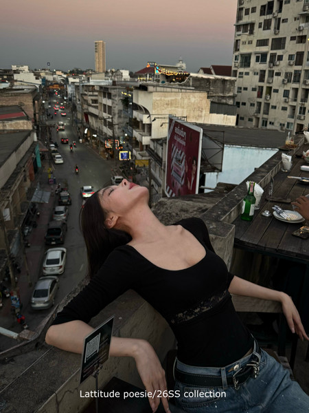 Woman wearing a black fitted top and jeans in an urban rooftop setting