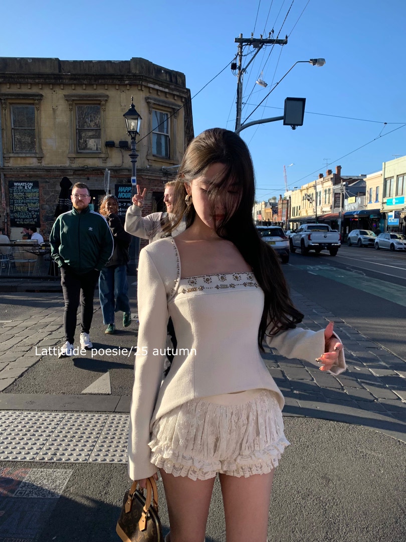 Woman wearing a cream long-sleeve top and lace mini skirt on a city street