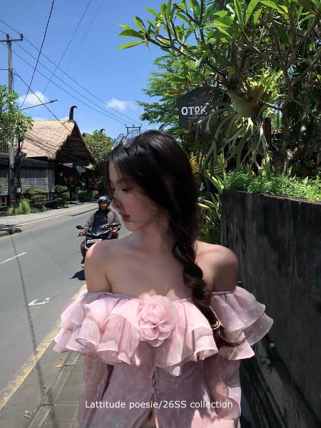 Woman wearing a pink off-shoulder ruffled dress outdoors