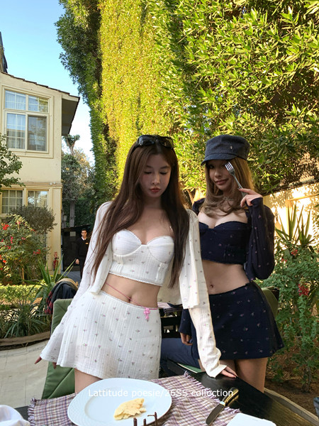 Two women wearing matching floral two-piece outfits outdoors at a patio table