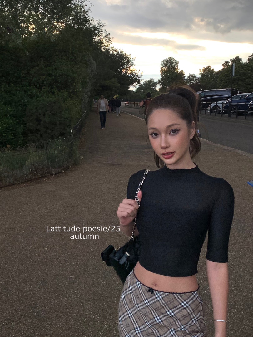 Woman wearing a black fitted top and plaid skirt outdoors at dusk
