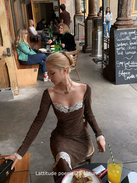 Woman wearing a brown checkered long-sleeve lace-trim dress at a restaurant