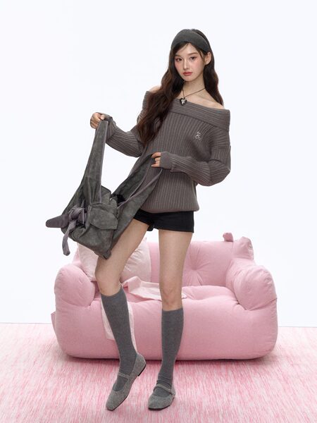 Model wearing a gray off-shoulder knit outfit and holding a gray shoulder bag