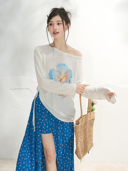 Model wearing a white off-shoulder long-sleeve top with a blue floral wrap skirt