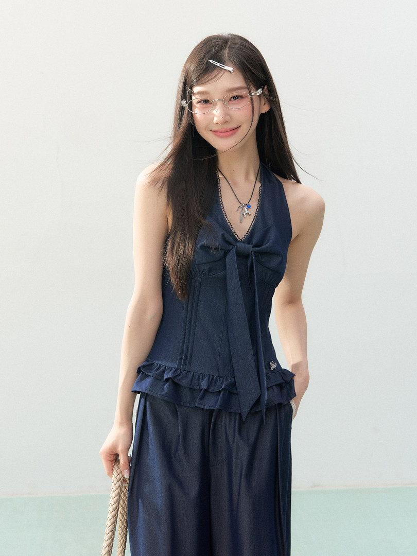 Model wearing a navy halter-style two-piece outfit with a bow detail