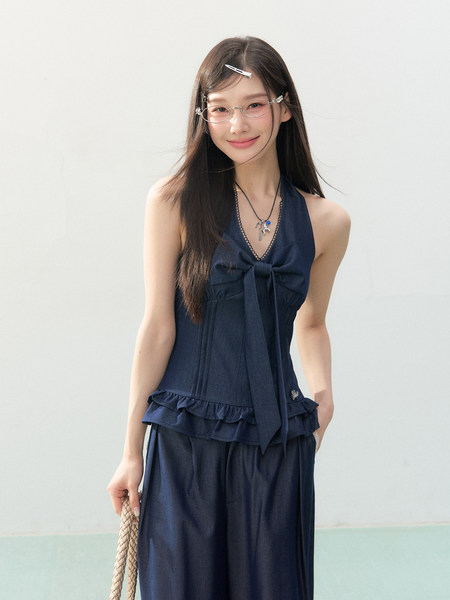 Model wearing a navy halter-style two-piece outfit with a bow detail