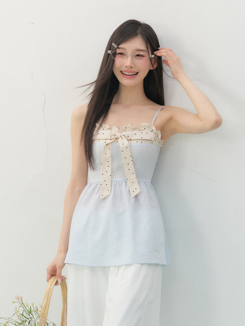 Light blue sleeveless dress with a polka dot bow detail worn by a model