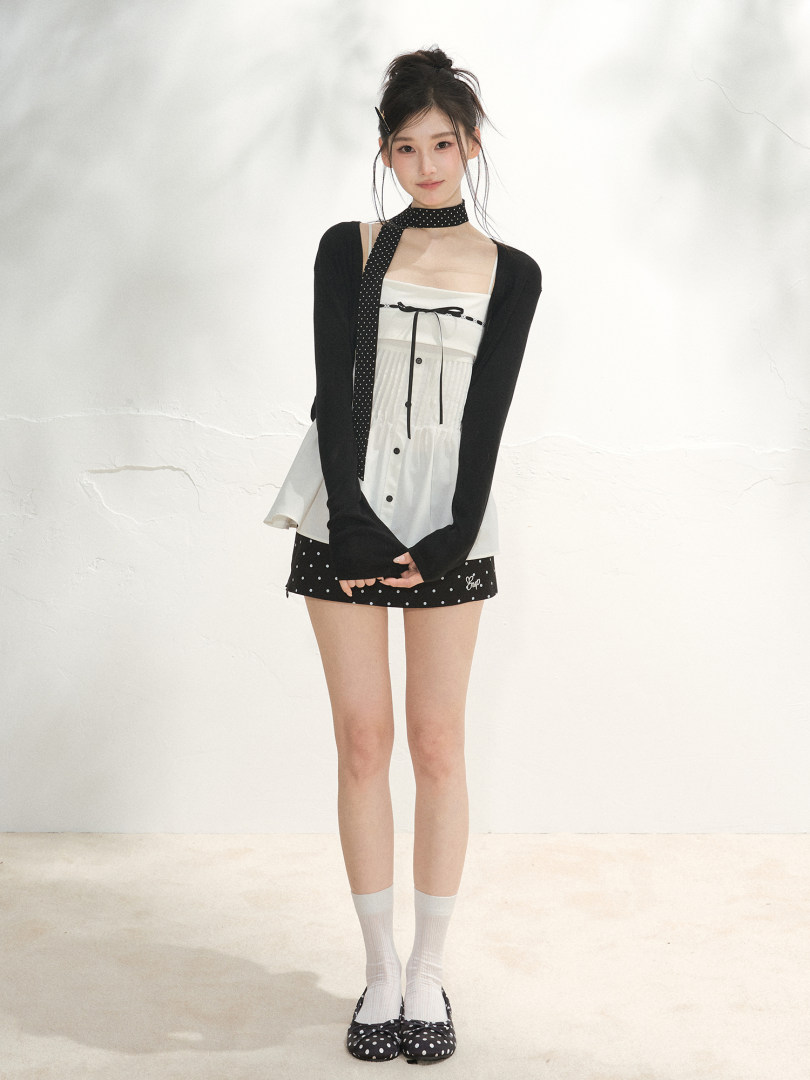 Model wearing a black and white layered mini dress outfit with polka dot details