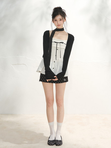 Model wearing a black and white layered mini dress outfit with polka dot details