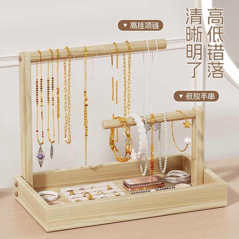 A wooden jewelry shelf displays a hand-held box of necklace