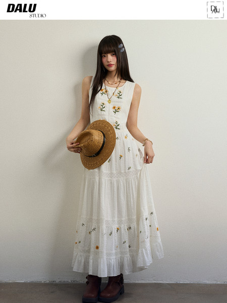 Model wearing a white floral sleeveless maxi dress with a straw hat