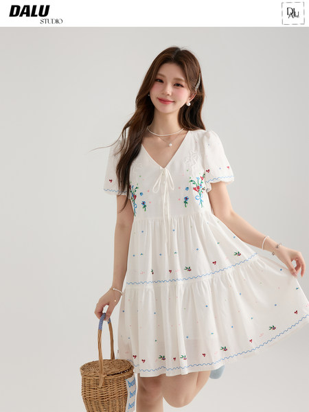 Young woman wearing a white embroidered short-sleeve dress with a basket bag