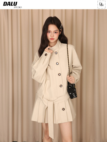 Beige belted coat and pleated skirt outfit worn by a model