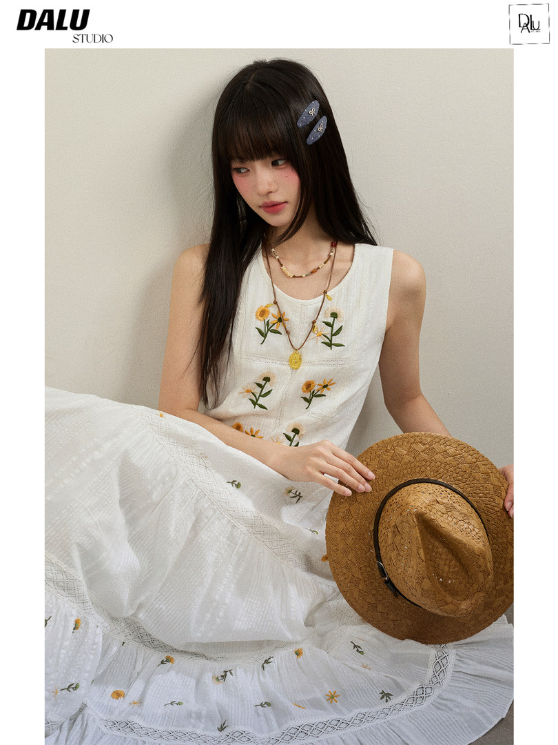 Model wearing a white sleeveless floral embroidered dress with a straw hat