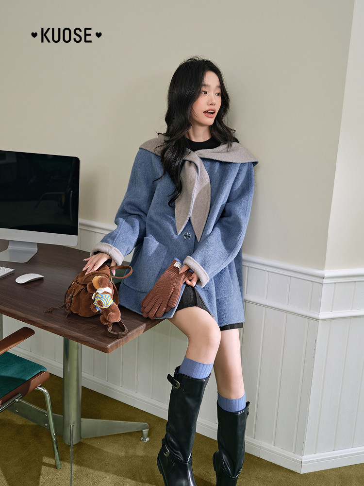 Model wearing a blue wool coat with scarf detail and black boots