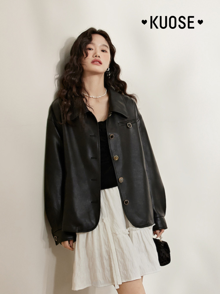 Model wearing a black leather jacket over a white skirt