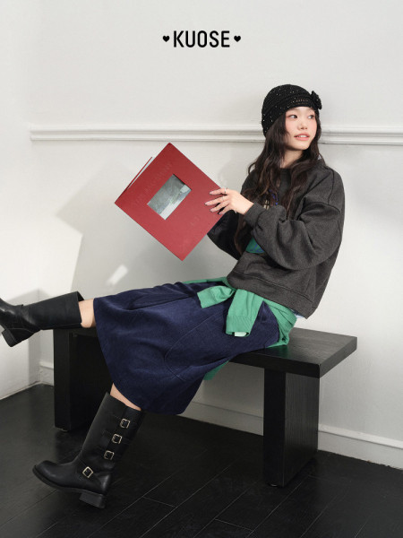 Model wearing a dark casual layered outfit with black boots and beanie