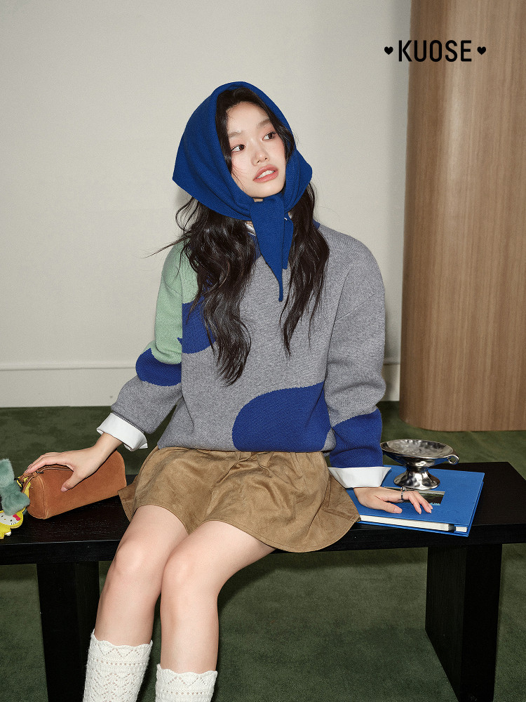Model wearing a blue and gray hooded sweater with a short brown skirt