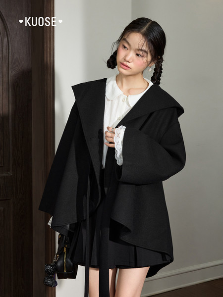Model wearing a black oversized coat with a white blouse