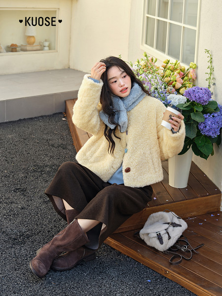 Model wearing a cream fuzzy jacket with a blue scarf and brown boots