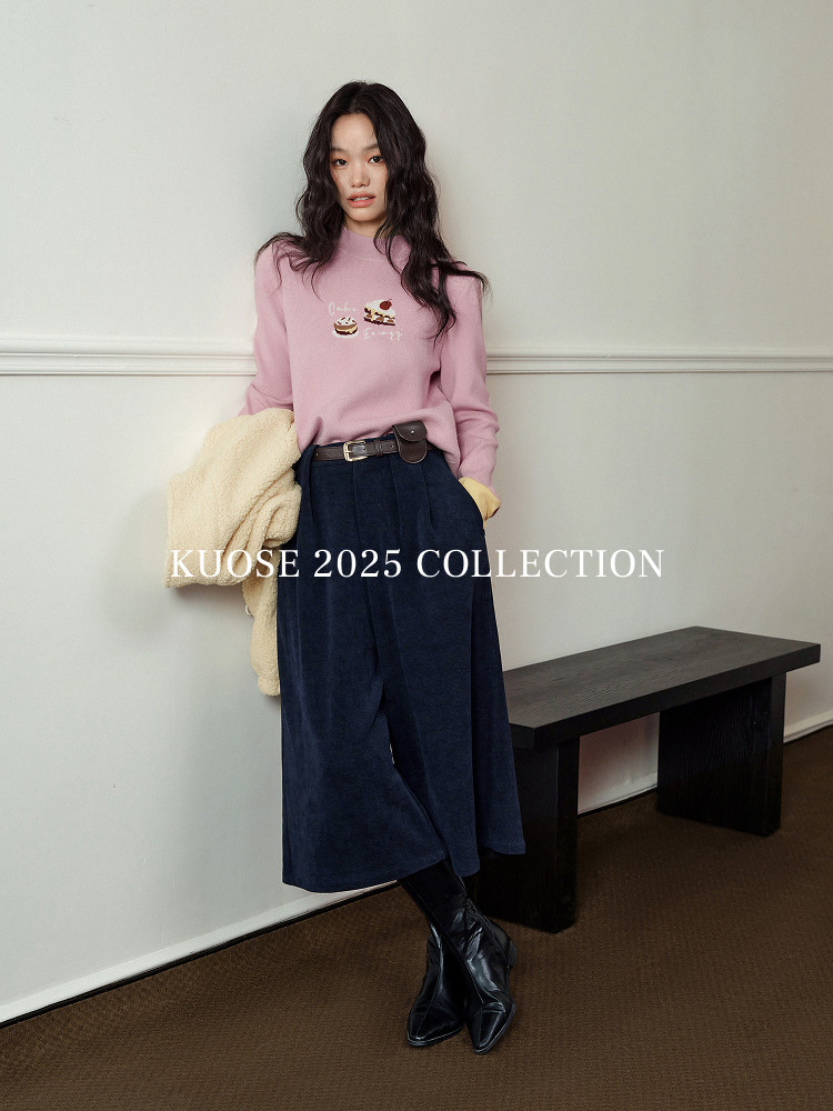 Model wearing a pink sweater and navy midi skirt with black boots
