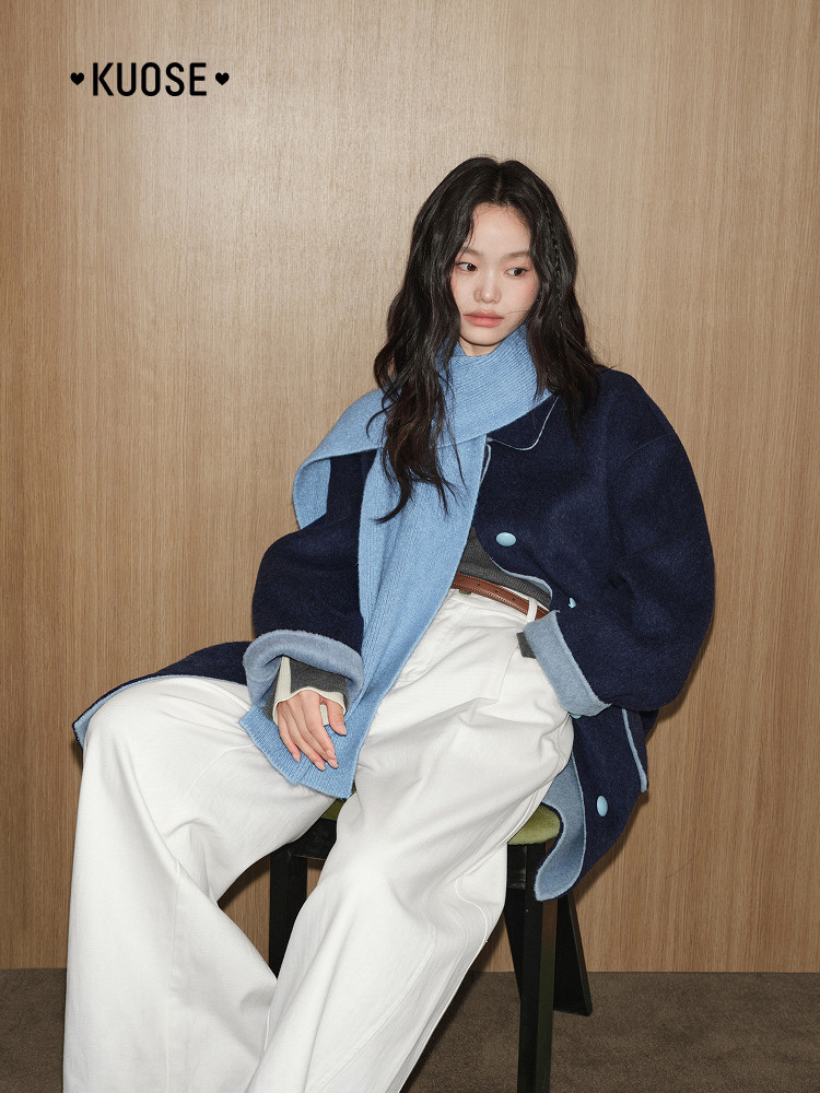 Model wearing a navy and light blue oversized coat with white pants
