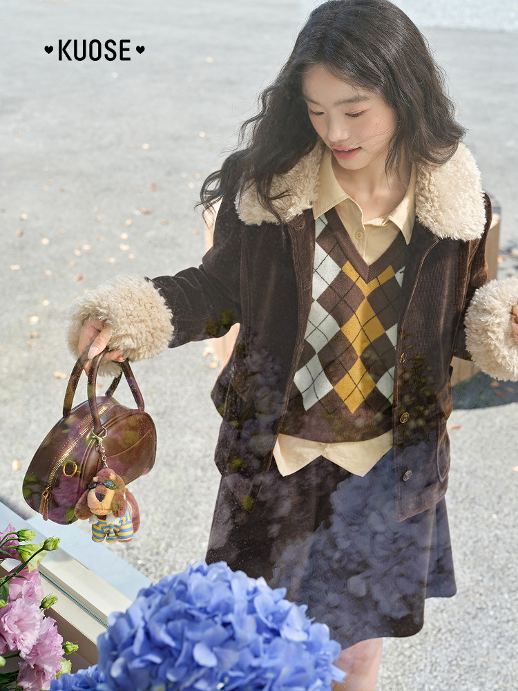 Woman modeling a brown shearling-collar coat outfit while holding a handbag
