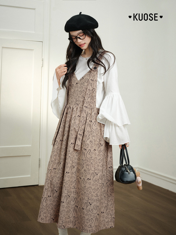 Model wearing a patterned brown pinafore dress over a white blouse