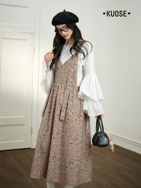 Model wearing a patterned brown pinafore dress over a white blouse