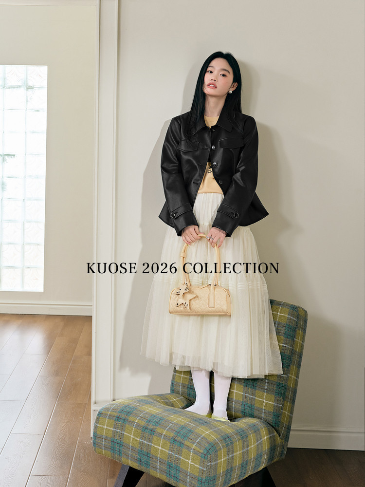 Model wearing a black leather jacket with a cream tulle skirt and beige handbag