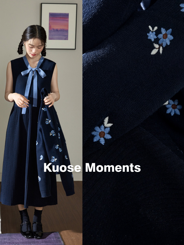 Navy sleeveless pleated dress with bow detail and floral embroidery on a model