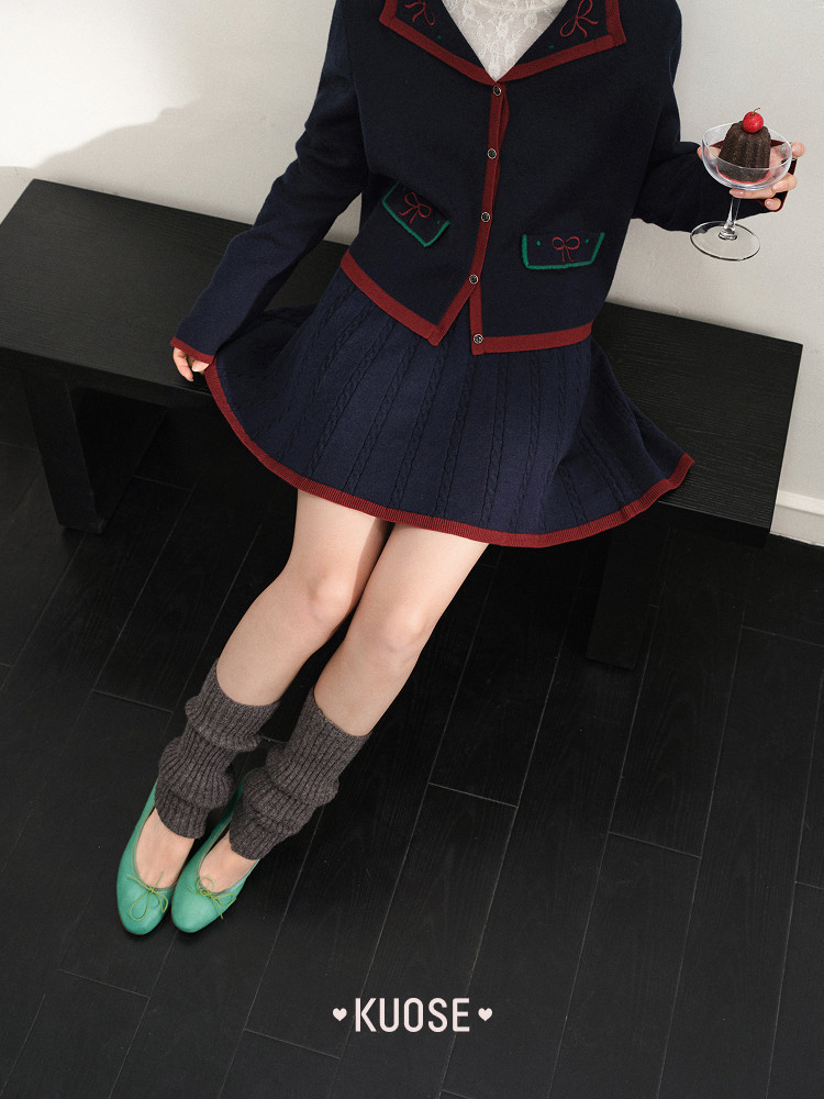 Model wearing a navy cardigan and pleated skirt with green flats and leg warmers