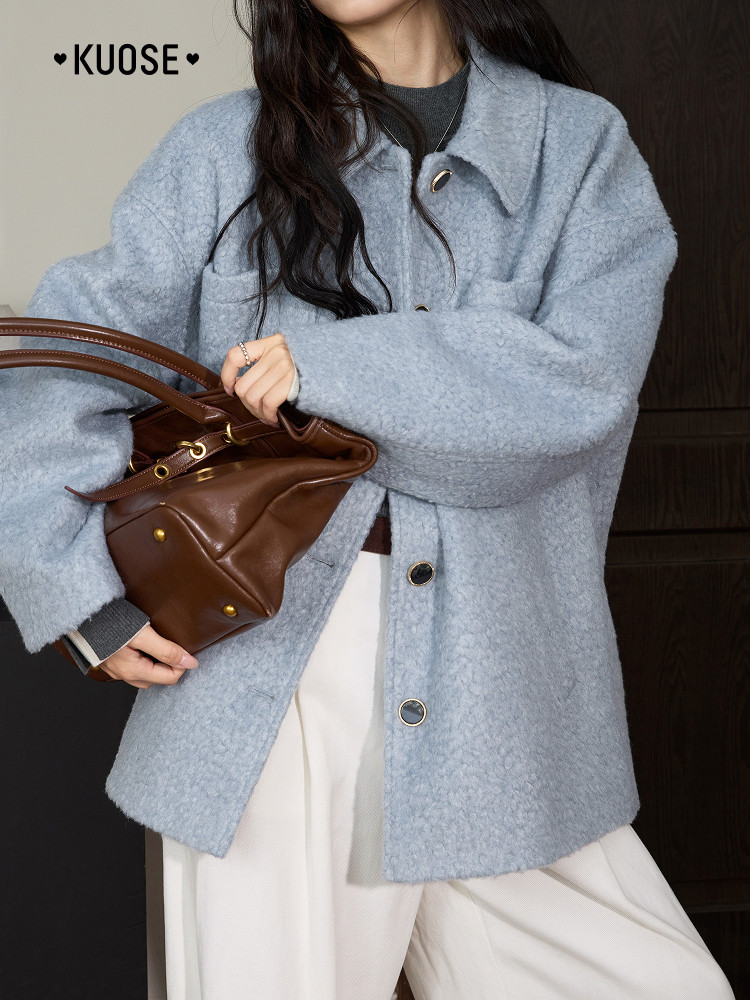 Light blue textured oversized coat worn by a model with a brown leather handbag