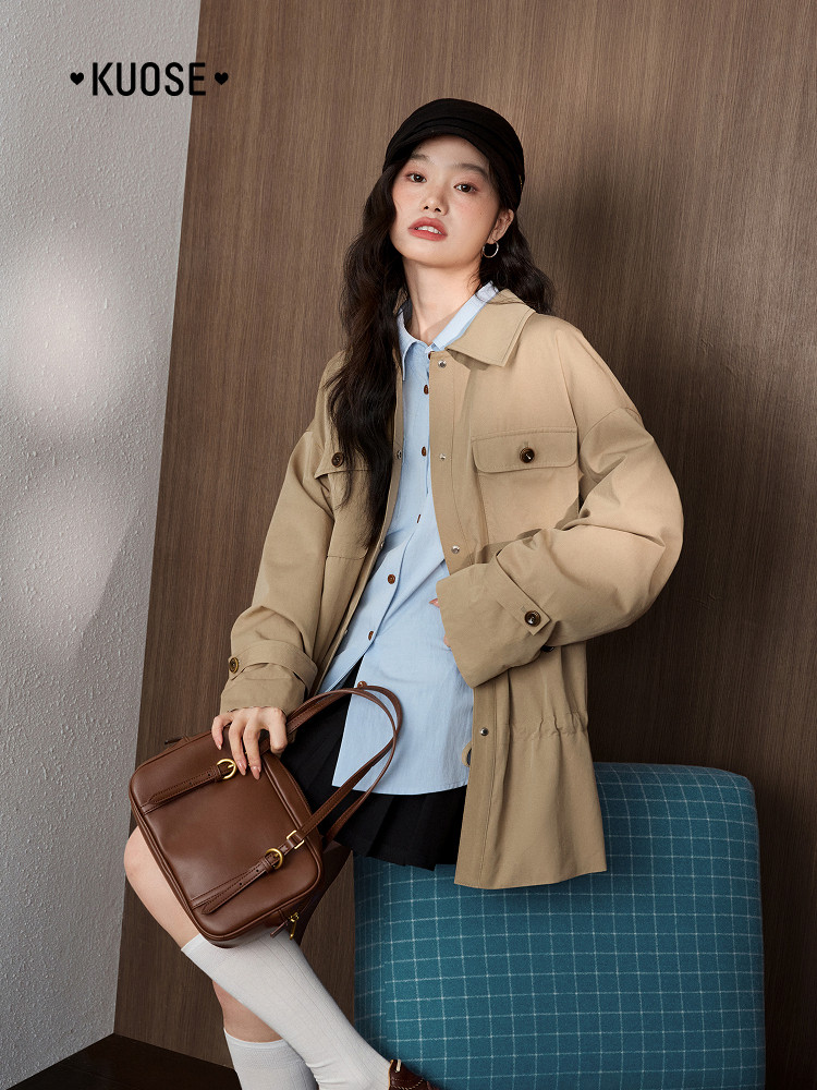 Model wearing a beige jacket with a blue shirt and brown shoulder bag