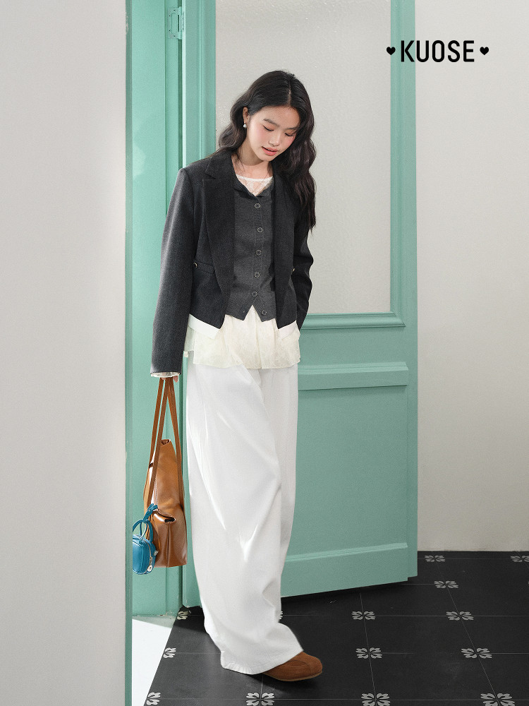 Model wearing a black cropped jacket with layered white outfit and brown bag