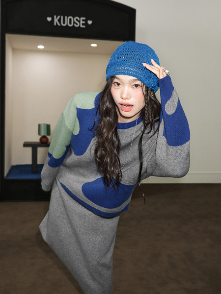 Model wearing a blue and gray knit sweater dress with a matching blue hat