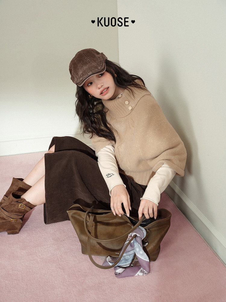 Model wearing a beige knit top with brown skirt, cap, boots, and a handbag