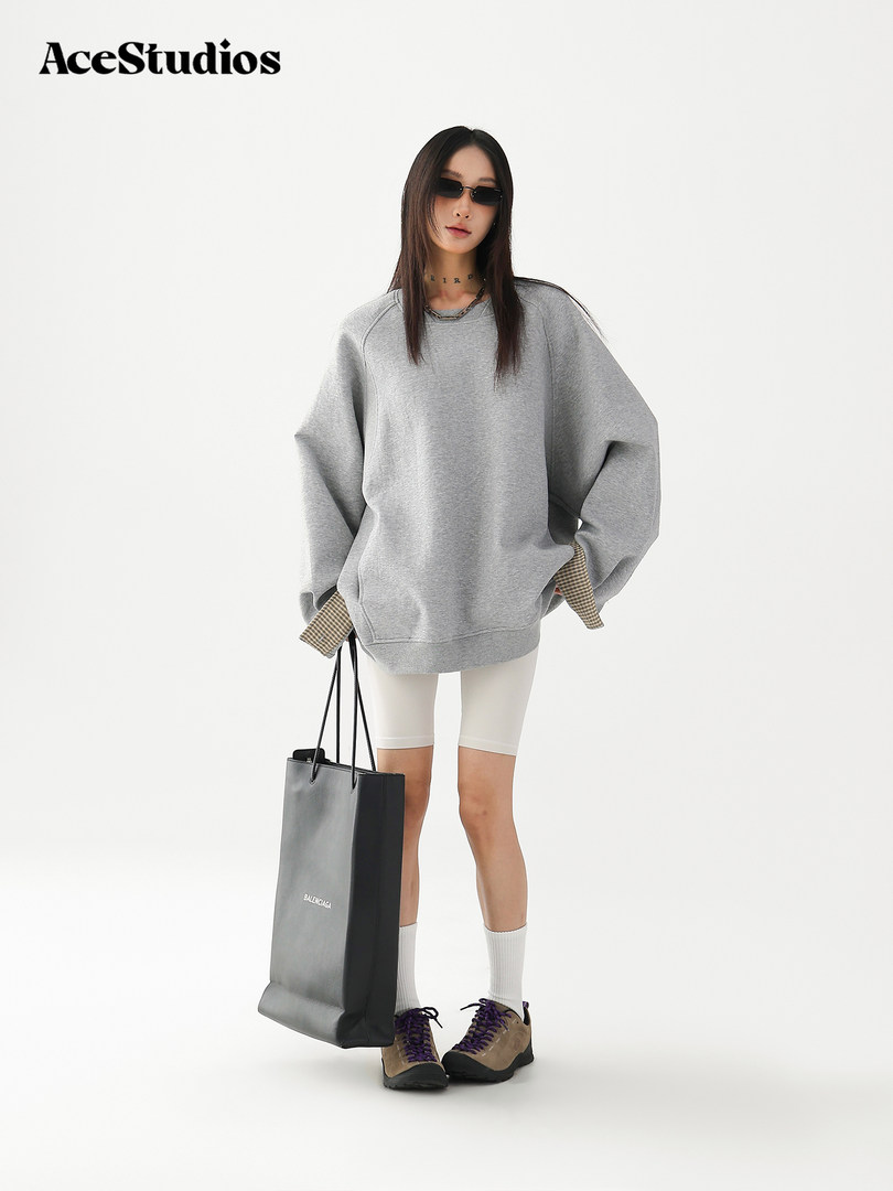 Model wearing an oversized gray sweatshirt with shorts and sneakers