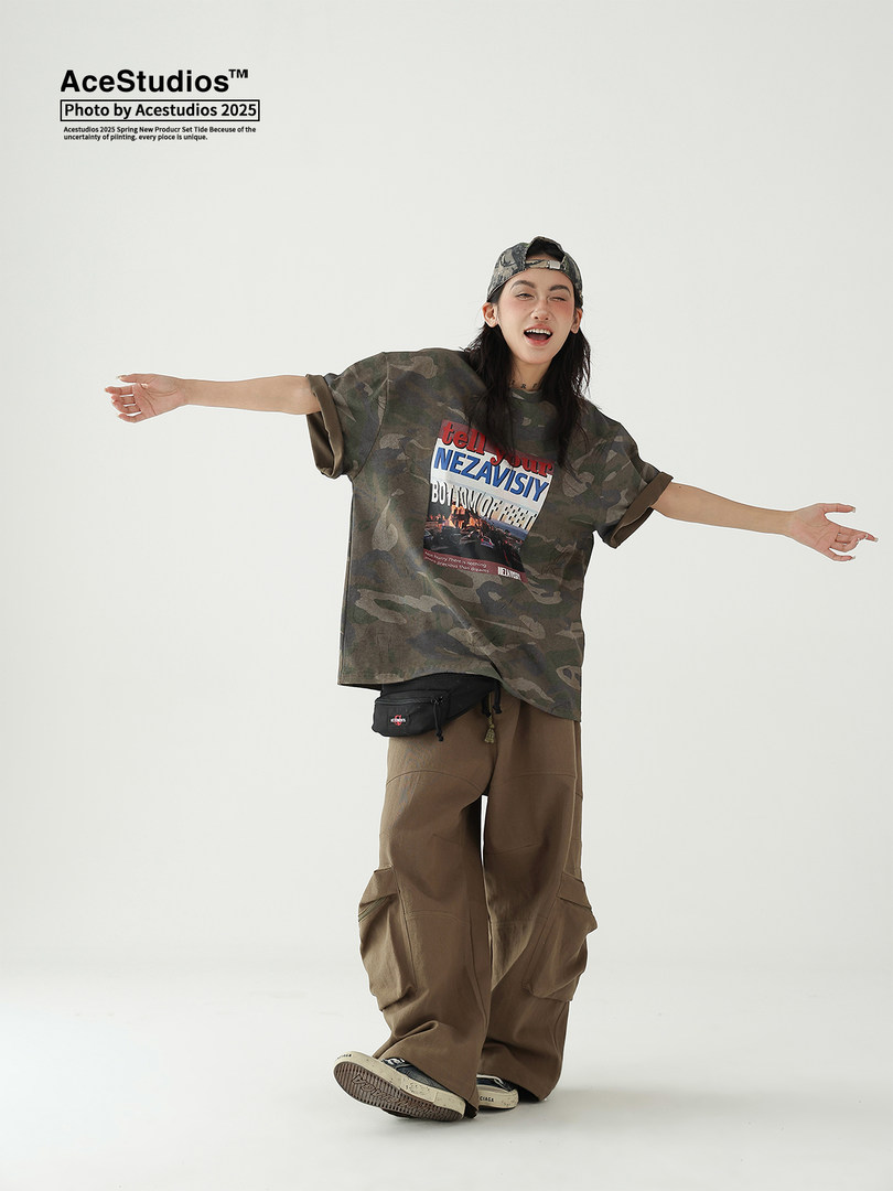 Model wearing oversized camo graphic T-shirt with baggy cargo pants and cap