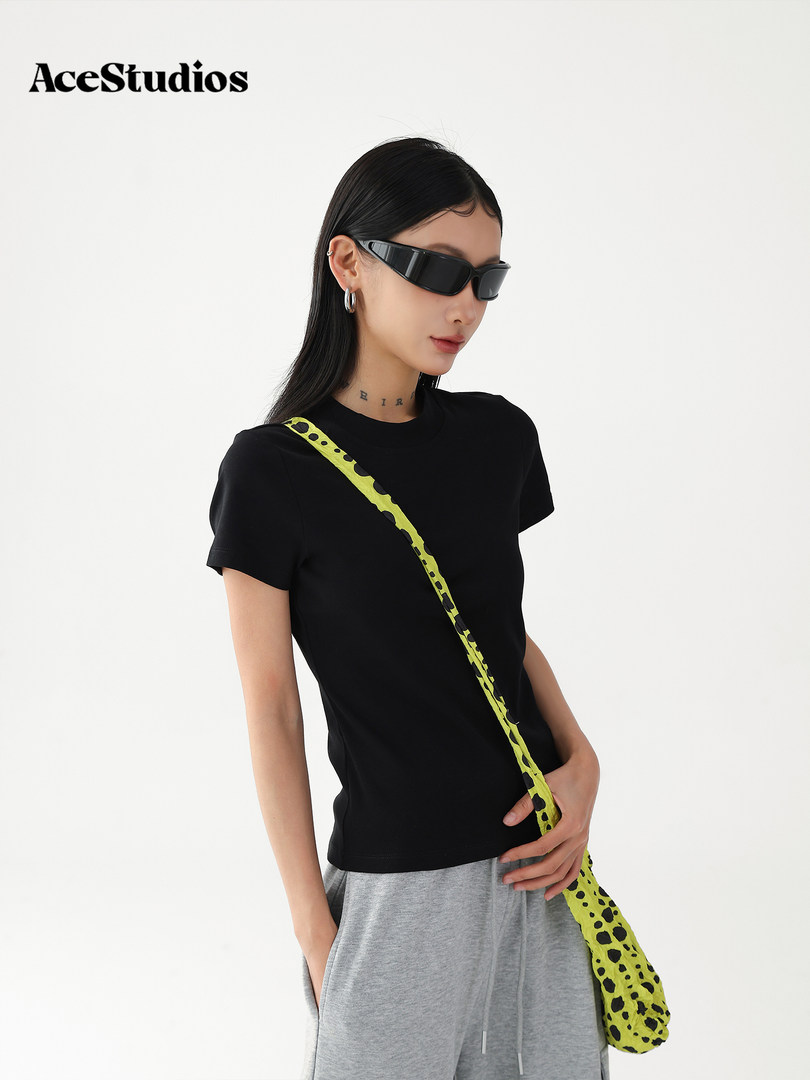 Black fitted T-shirt worn by a model with a neon green crossbody bag