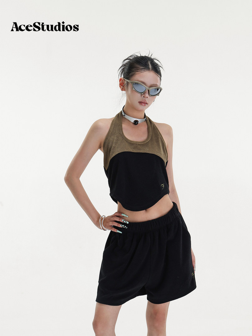 Model wearing a black and olive halter top with black shorts