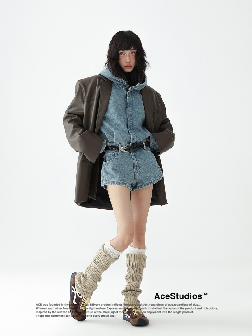 Model wearing a layered denim outfit with oversized jacket and leg warmers