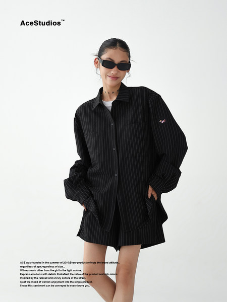 Model wearing an oversized black pinstriped shirt and matching shorts