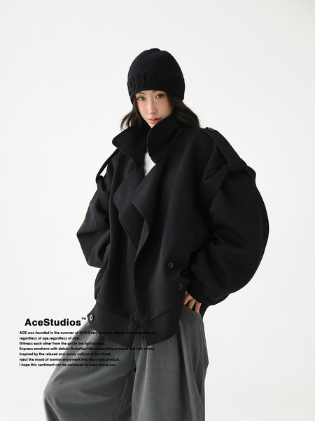 Model wearing an oversized black coat with a black beanie