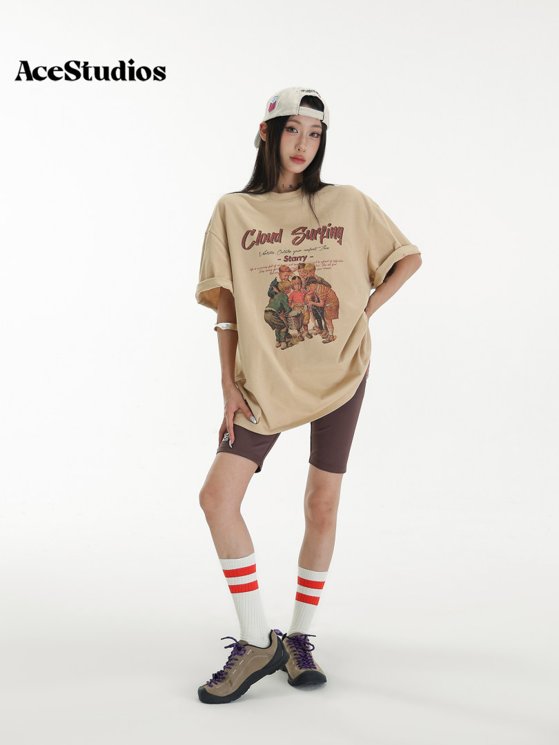 Model wearing a beige graphic oversized T-shirt with biker shorts and sneakers