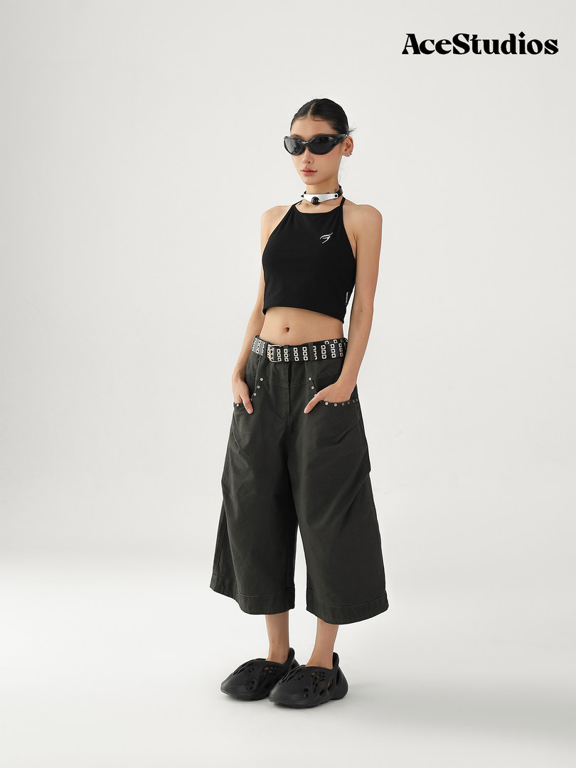 Model wearing a black halter crop top with wide-leg pants and black shoes